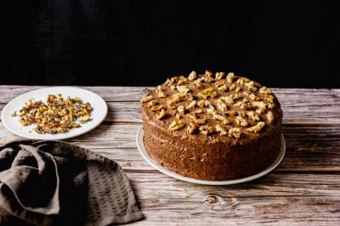 Ev yapımı çikolatalı pasta, kavrulmuş cevizli tatlı bisküvi, tatlı tatlı, ahşap arka planda kahverengi gıda rengi, yanında spatula ve ezilmiş ceviz.