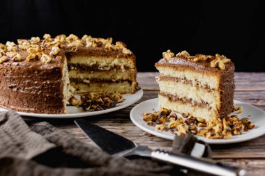 Ev yapımı çikolatalı pasta, kavrulmuş cevizli tatlı bisküvi, tatlı tatlı, ahşap arka planda kahverengi gıda rengi, yanında spatula ve ezilmiş ceviz.