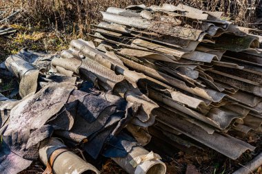 Kırık kayrak parçaları, çatıdan alınan, büyük bir yığın toplanır bahçede kuru çimenlerin arasında, sıcak güneşin altında, bir yığın yapı malzemesi