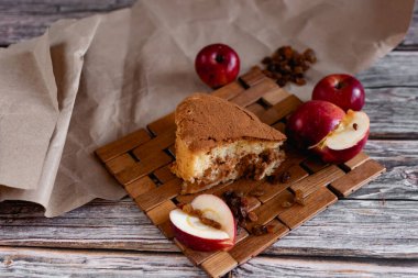 Elma ve kuru üzümlü sünger kek, mis kokulu tarçın serpiştirilmiş, tatlı olarak havadar tatlı hamur, tatlı olarak sağlıklı hamur işleri, ahşap ve parşömen üzerinde servis edilen, un pişirme