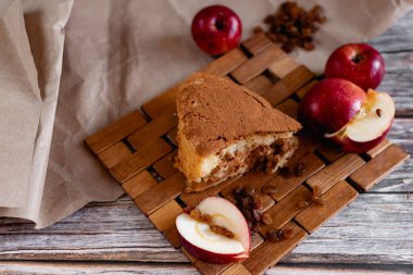 Elma ve kuru üzümlü sünger kek, mis kokulu tarçın serpiştirilmiş, tatlı olarak havadar tatlı hamur, tatlı olarak sağlıklı hamur işleri, ahşap ve parşömen üzerinde servis edilen, un pişirme