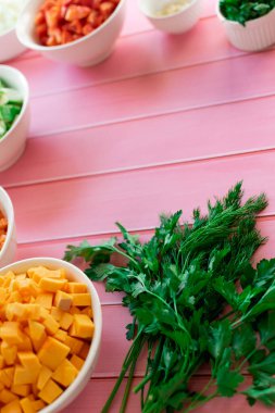 Taze yeşil maydanoz ve pembe ahşap arka planda dereotu, mutfakta yemek pişirmek için hazırlanan malzemeler, baharat yerine kokulu gıda katkı maddeleri.