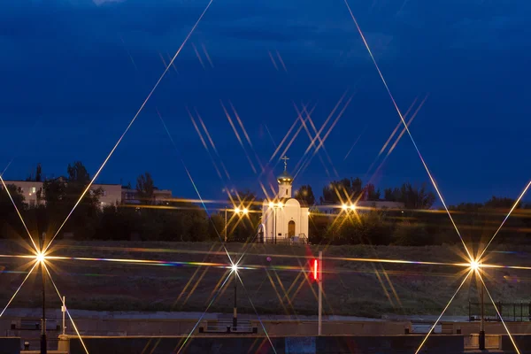 Una pequeña iglesia con iluminación nocturna. Luces y filtro de estrellas —  Fotos de Stock