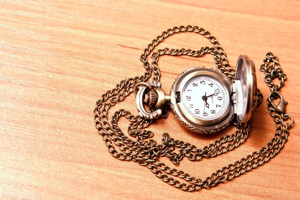 Kapesní hodinky řetěz na pozadí dřevěný pracovní stůl — Stock fotografie