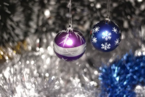 Two Christmas tree bulb hanging on a background of new year's tinsel — Stock Photo, Image