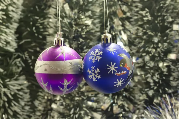 Two Christmas tree bulb hanging on a background of new year's tinsel — Stock Photo, Image