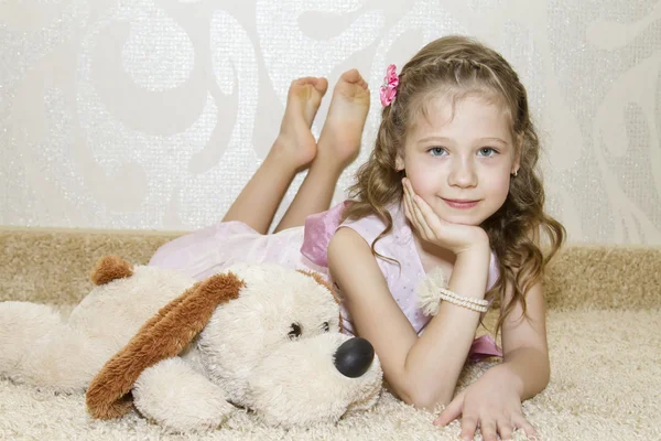 Niña acostada en la alfombra con un perro de peluche —  Fotos de Stock