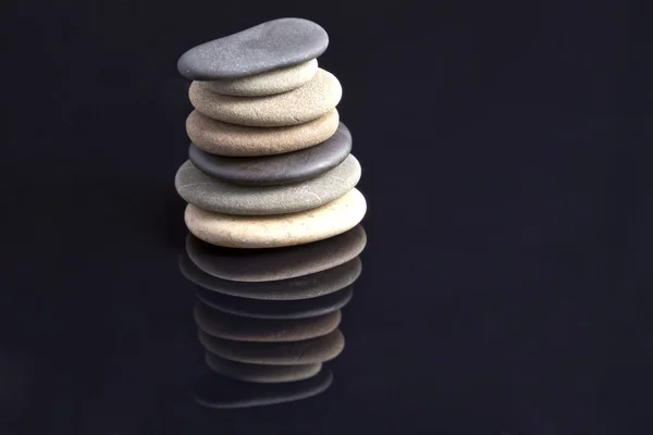 Pedras do mar colocadas em pilhas refletidas no preto — Fotografia de Stock