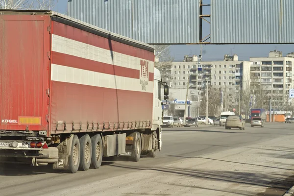 Red truck is going down dirty and dusty city road. — Stock Photo, Image