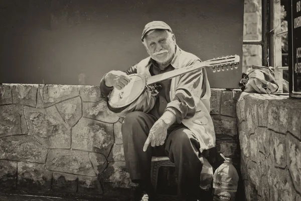 Alter Straßenmusiker mit der Gitarre in der Hand — Stockfoto