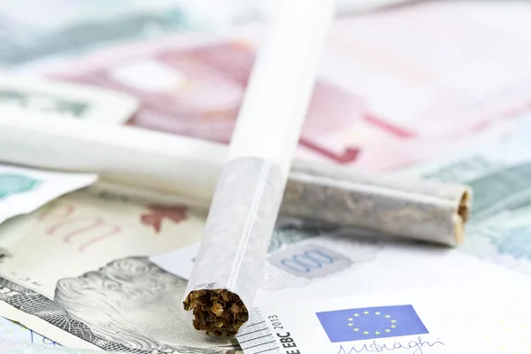 Two cigarettes lying on the money — Stock Photo, Image