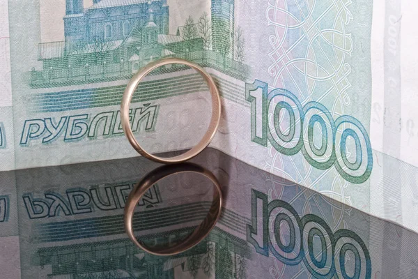 Gouden bruiloft ring op de achtergrond van bankbiljetten duizend roebels — Stockfoto