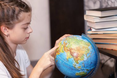 Kız dünyaya ilgiyle bakıyor ve kendine yabancı ülkeler buluyor..