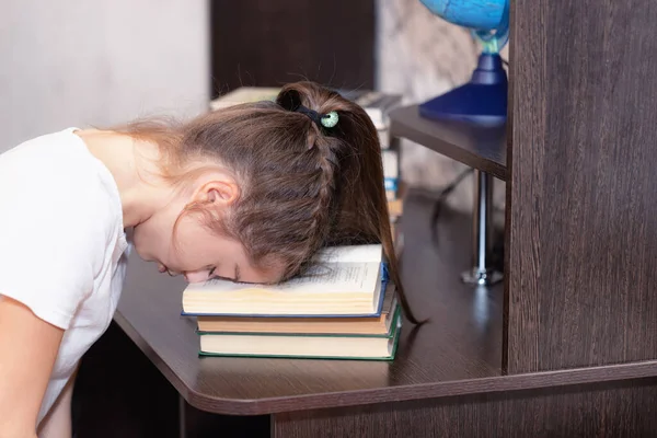 A middle school student is tired of homework and lies with her head on an open book.