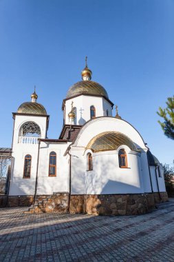 Beyaz kampları, çan kulesi ve açık havada yaldızlı kubbeleri olan ortodoks kilisesi.