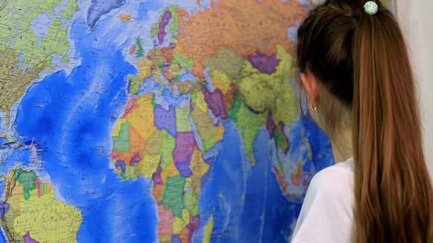 Дівчина шкільного віку вивчає розташування країн на карті світу — стокове відео