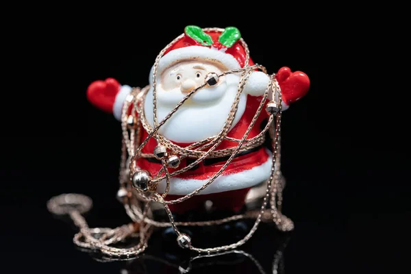 玩具圣诞老人被一条纤细的女性金项链包裹着 — 图库照片