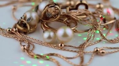 Beyaz incili altın mücevherler beyaz bir platformda dönüyor.