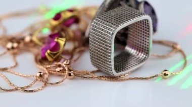 Büyük kırmızı yakut, yüzük, zincir ve kolye ile altın küpeler beyaz bir yüzey üzerinde döner