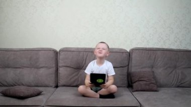 Bir anaokulu çocuğu tabletten müzik dinler.