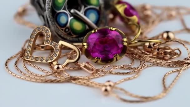 Pendientes de oro con grandes rubíes rojos, anillos, cadena y colgante giran sobre una superficie blanca — Vídeos de Stock