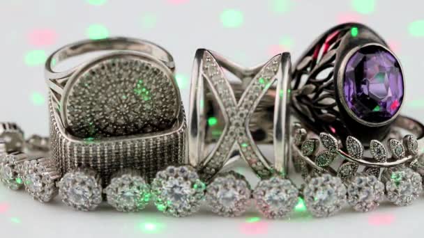 Zilveren ringen van verschillende vormen worden verlicht door chaotische kleurenlaserstralen — Stockvideo