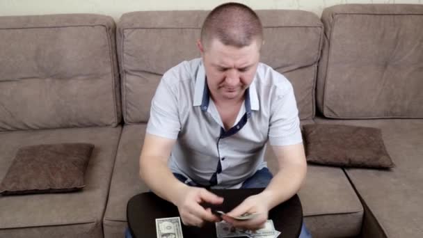 Ένας μεσήλικας που κάθεται στον καναπέ μετράει τα λεφτά του. — Αρχείο Βίντεο