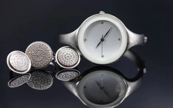 Elegantní dámské hodinky v kovovém pouzdře a šperky ze stříbra — Stock fotografie