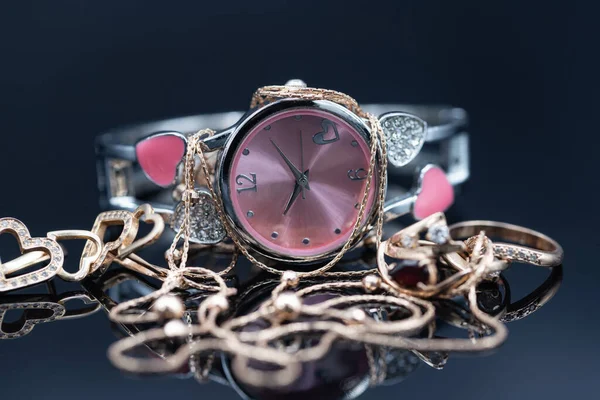 Eleganter goldener Damenschmuck und Uhr mit rosa Zifferblatt — Stockfoto