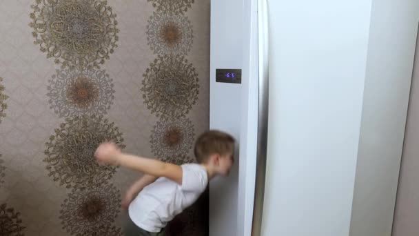 Маленький мальчик открывает холодильник на кухне и выбирает на долгое время продукты — стоковое видео
