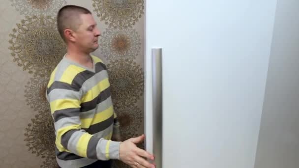Мужчина открывает холодильник на кухне и берет оттуда стакан сока.. — стоковое видео