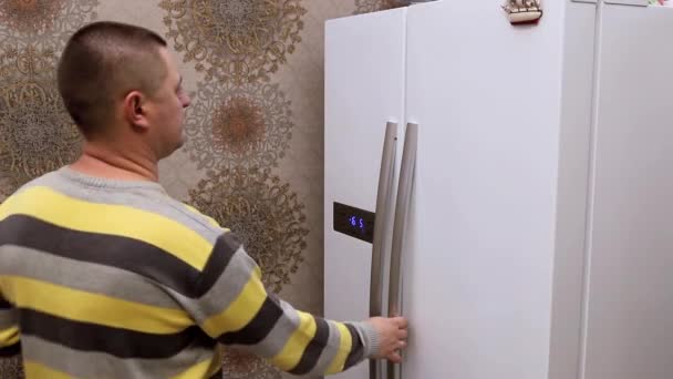 Человек кладет неполную бутылку молока обратно в холодильник — стоковое видео