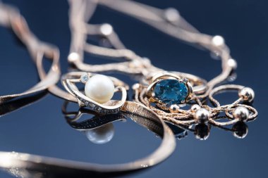 Farklı değerli taşları olan altın yüzükler güzel altın zincirlerle çevrili.