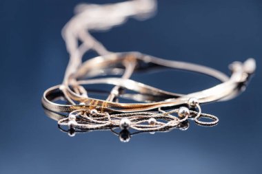 Farklı değerli taşları olan altın yüzükler güzel altın zincirlerle çevrili.