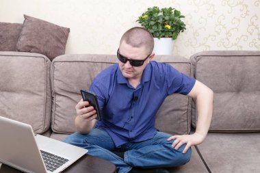 Mavi tişörtlü bir adam blogunda cep telefonuyla selfie çekiyor..