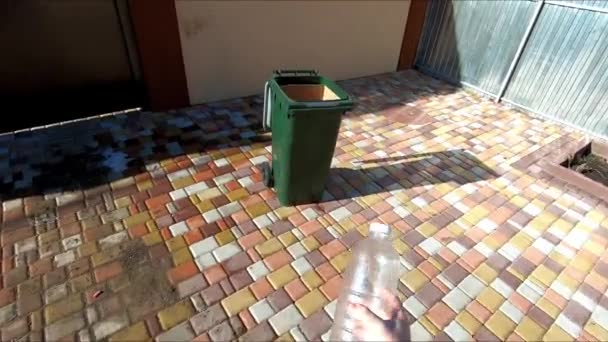 Plastic flessen in een vuilnisbak gooien op het grondgebied van een particulier huis — Stockvideo