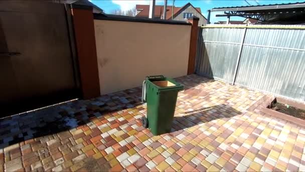 Throwing plastic bottles into a garbage can on the territory of a private house — Stock Video