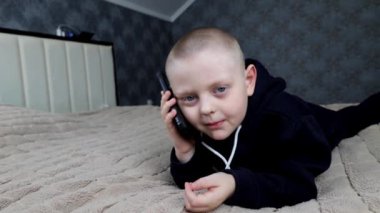 Anaokulu çocuğu telefonda konuşuyor. Yatakta yatıyor.