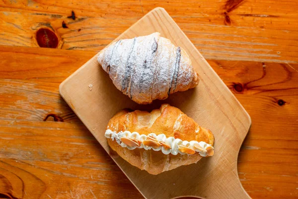 Croissant Wypełniony Śmietaną Posypką Cukrem Drewnianej Podłodze — Zdjęcie stockowe