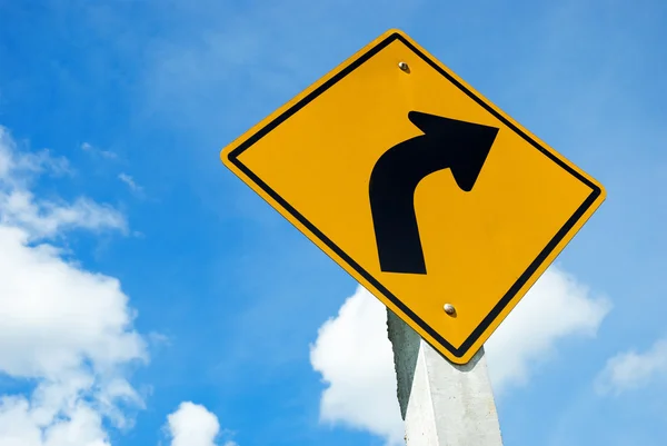 Weg ondertekenen waarschuwing van gevaarlijke links curve op blauwe hemel — Stockfoto