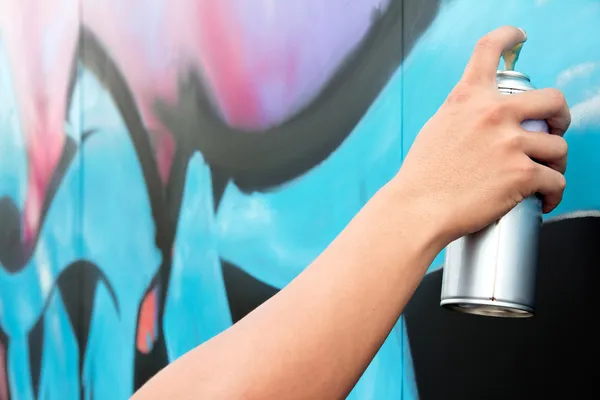 Hand som håller sprayfärg på vägg graffiti — Stockfoto