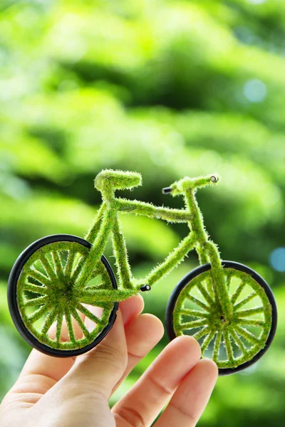 Mão segurando artesanato bicicleta verde — Fotografia de Stock