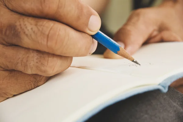 Hombre escribiendo en cuaderno de bocetos —  Fotos de Stock