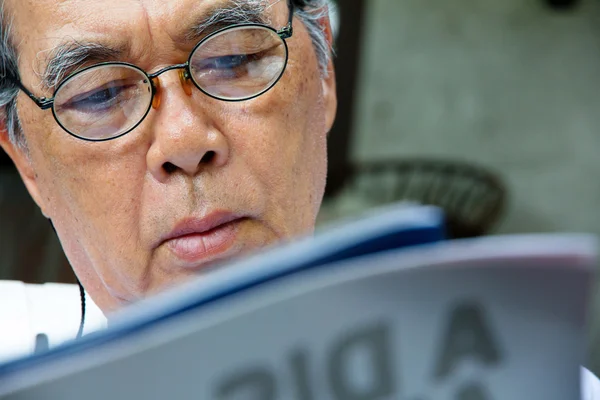 Hombre mayor relajándose en casa leyendo un libro — Foto de Stock