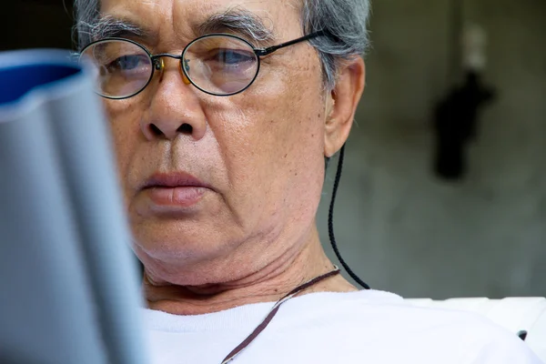 Hombre mayor relajándose en casa leyendo un libro — Foto de Stock