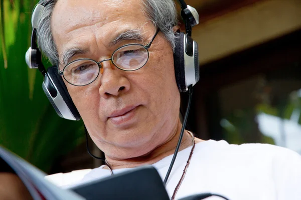 Senior man enjoying music on his tablet