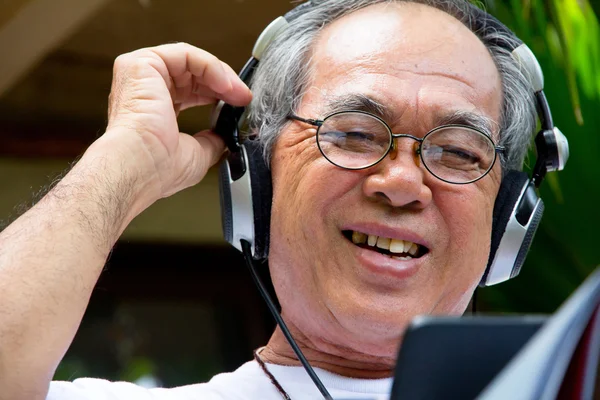 Senior man enjoying music on his tablet — Stock Photo, Image