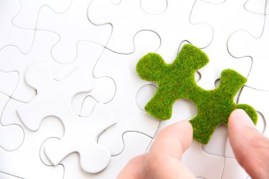 Hand holding a green puzzle piece clipart