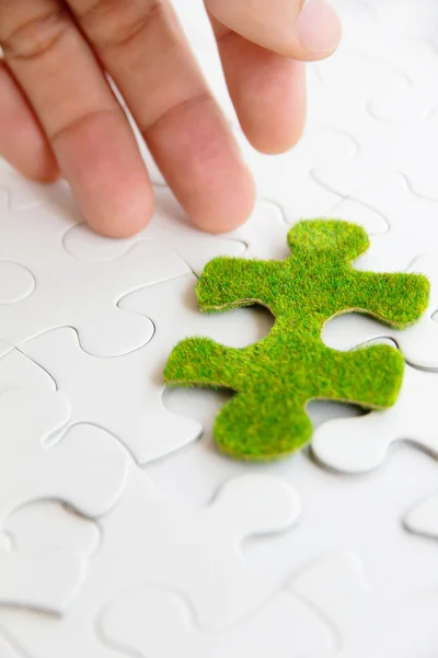 Рука держит зеленый кусочек головоломки — стоковое фото