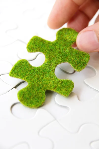 Mão segurando uma peça de puzzle verde — Fotografia de Stock